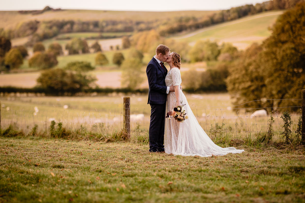 Kissing bride & groom with the hilles around Combe Gibbet in the background