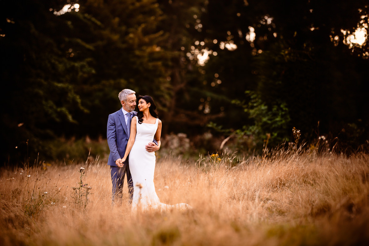 Couple pose in log grass during golden hour at The Retreat at Elcot Park